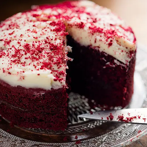 A red velvet cake with white frosting and sprinkles.